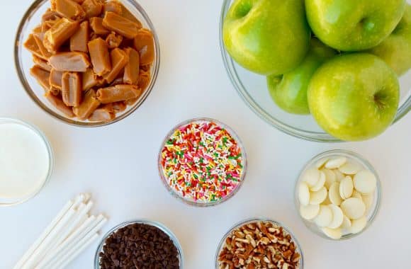 Ingredients for Easy Caramel Apples, including soft caramels, green apples, sticks, sprinkles, nuts and candy melts