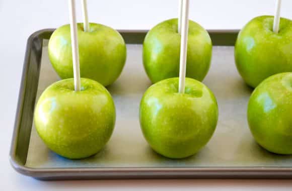 Granny Smith Apples with lollipop sticks on parchment paper-lined baking sheet