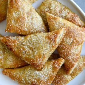 Easy peach turnovers topped with sanding sugar on a serving plate.