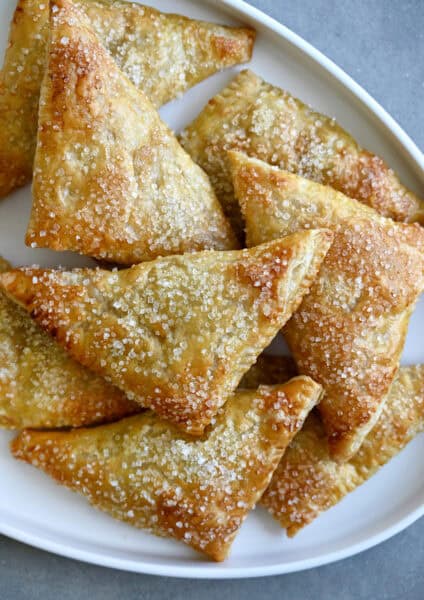 Easy peach turnovers topped with sanding sugar on a serving plate.