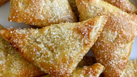 Easy peach turnovers topped with sanding sugar on a serving plate.