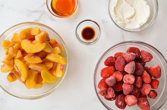 Glass bowls filled with fruit, yogurt, honey and vanilla extract