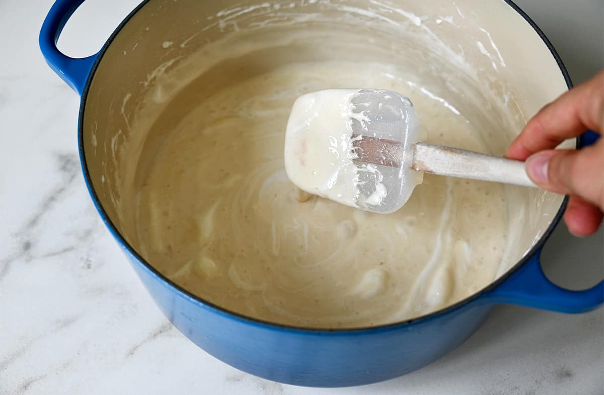 A spatula stirs melted marshmallows in a large stockpot.