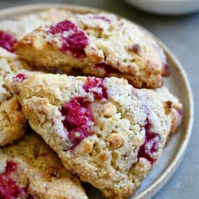 White chocolate raspberry scones piled atop each other on a plate.