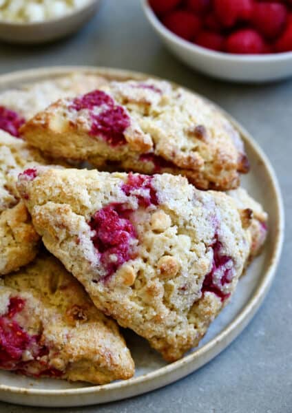 White chocolate raspberry scones piled atop each other on a plate.