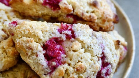 White chocolate raspberry scones piled atop each other on a plate.
