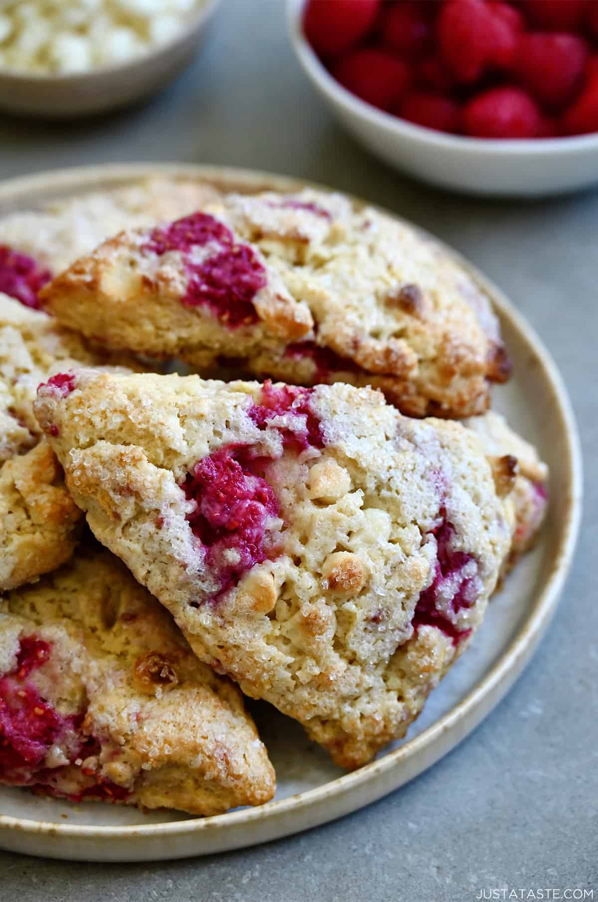 White chocolate raspberry scones piled atop each other on a plate.