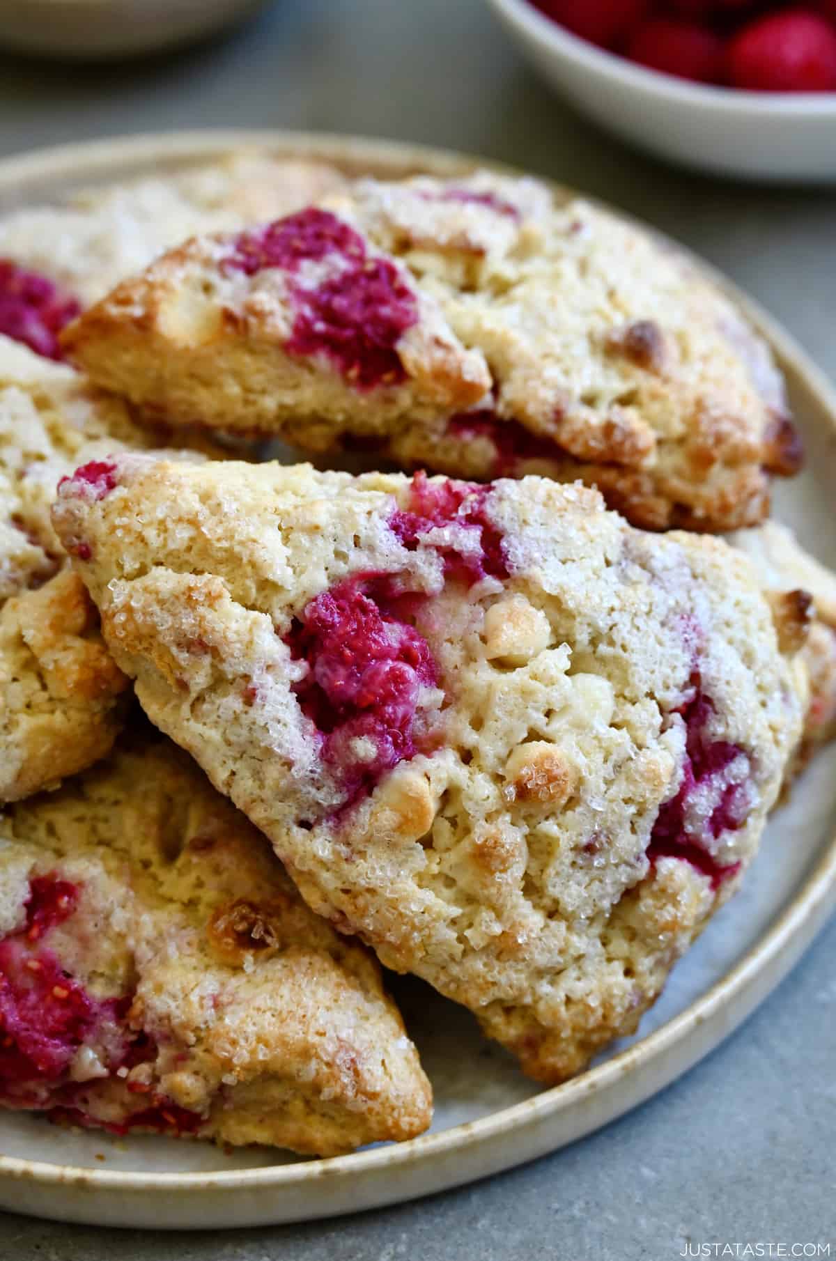 Raspberry scones studded with white chocolate chips on a plate.