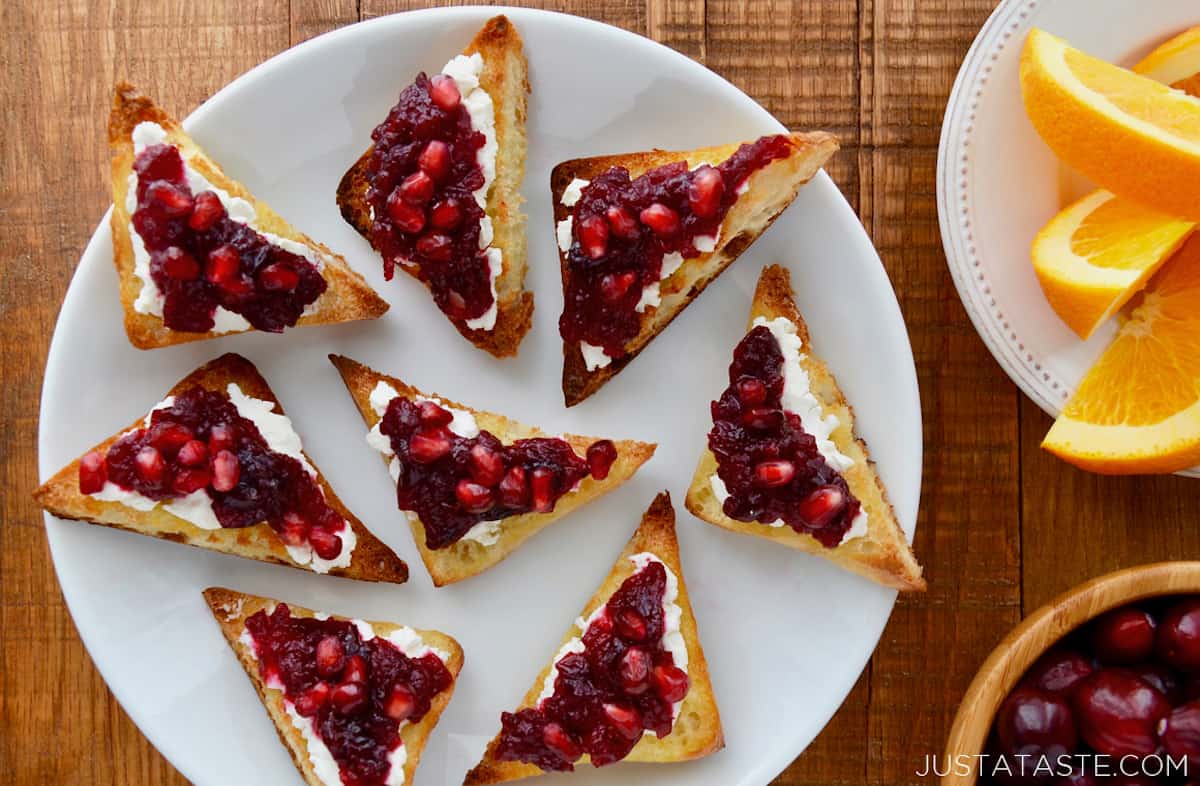 Pieces of toast topped with goat cheese and cranberry sauce on a white plate.