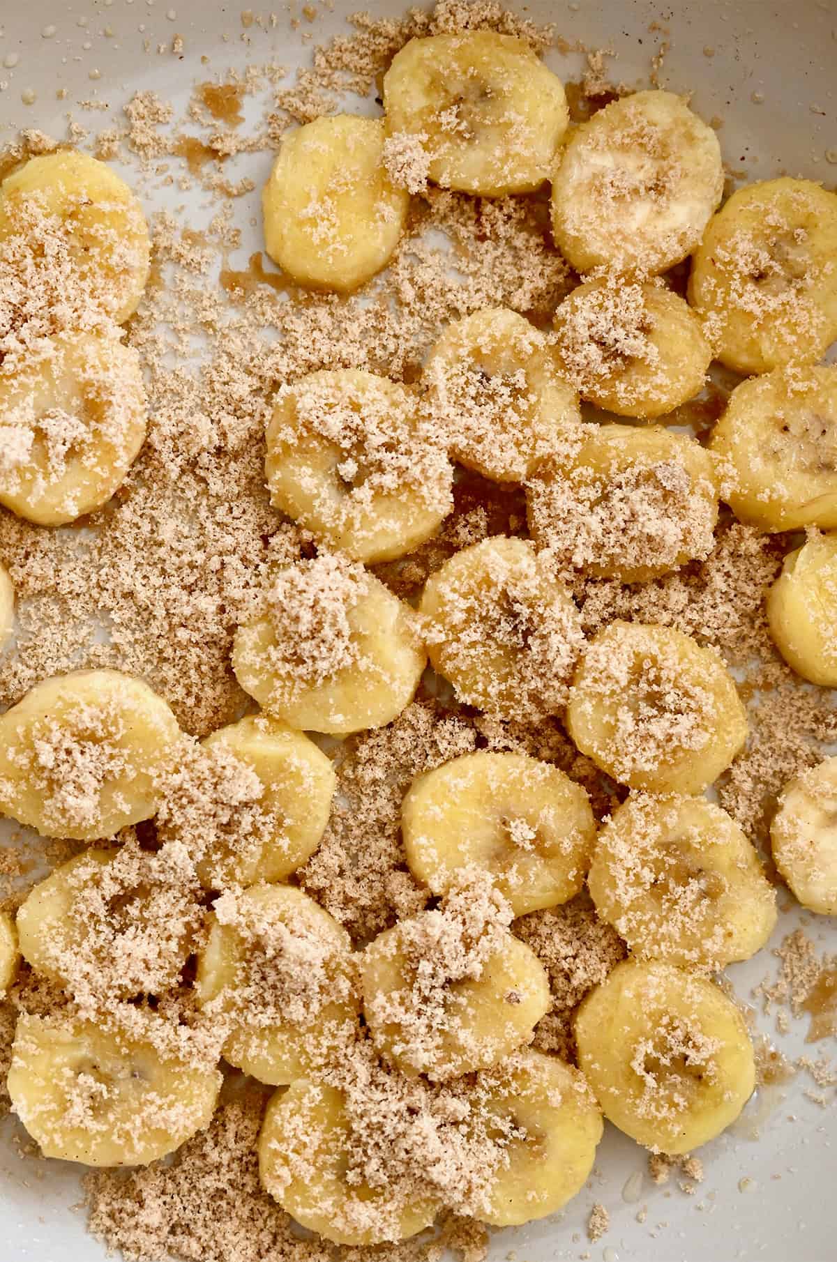 Sliced bananas in a large skillet with brown sugar.