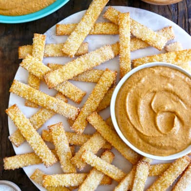 A top down view of pie crust fries on a white platter with bowls of pumpkin dip