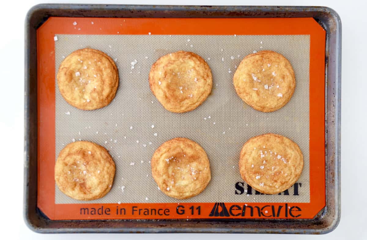 Caramel-stuffed snickerdoodles cooling on a baking sheet.