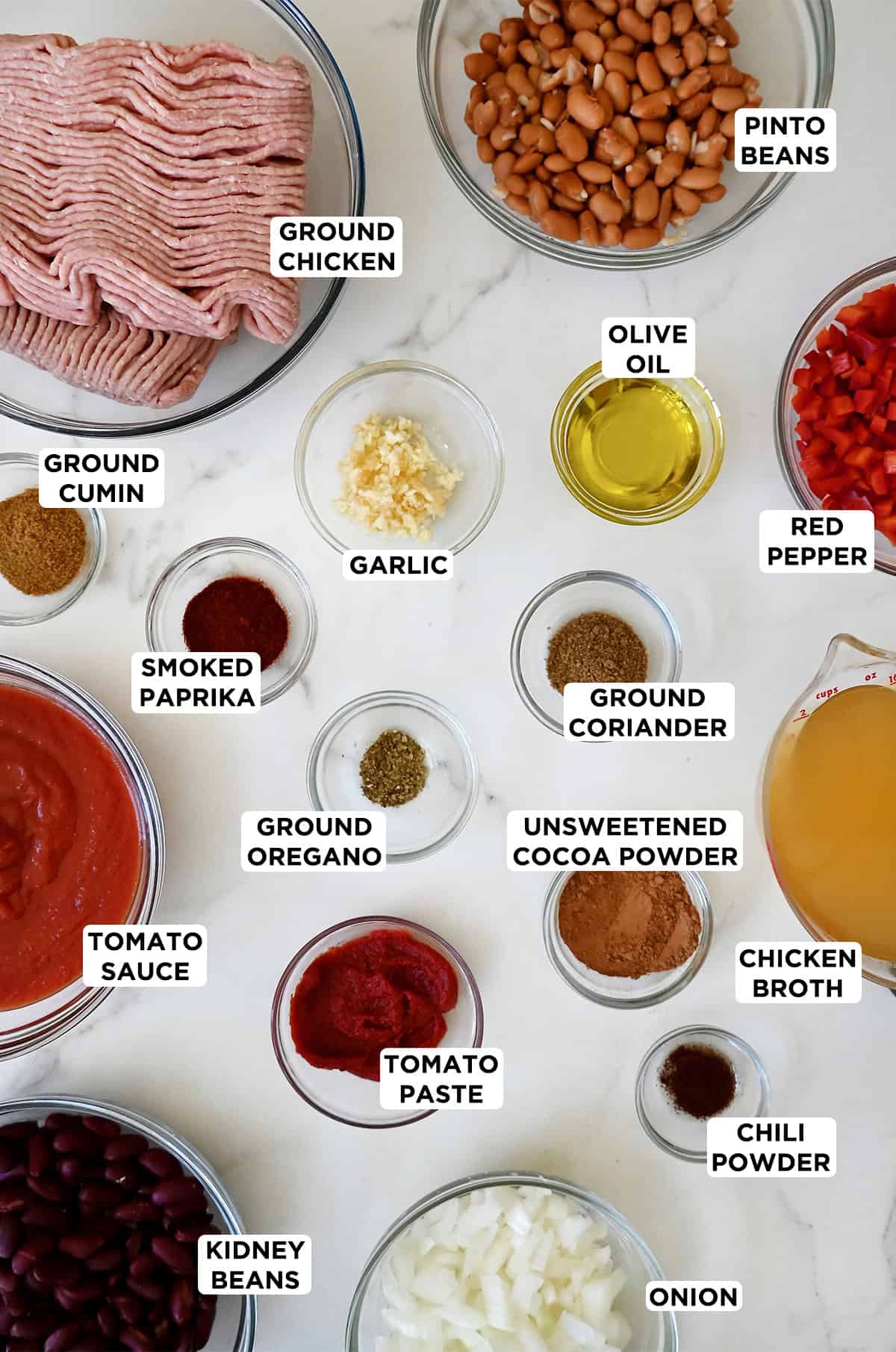 Various sizes of glass bowls containing the ingredients needed to make healthy slow cooker chili with ground chicken.
