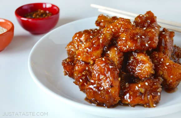 A white plate containing Baked Orange Chicken and chopsticks