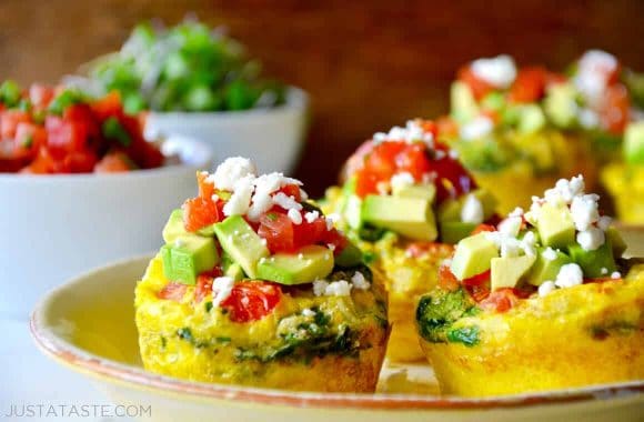 A plate containing Egg Muffins topped with avocado, salsa and cheese