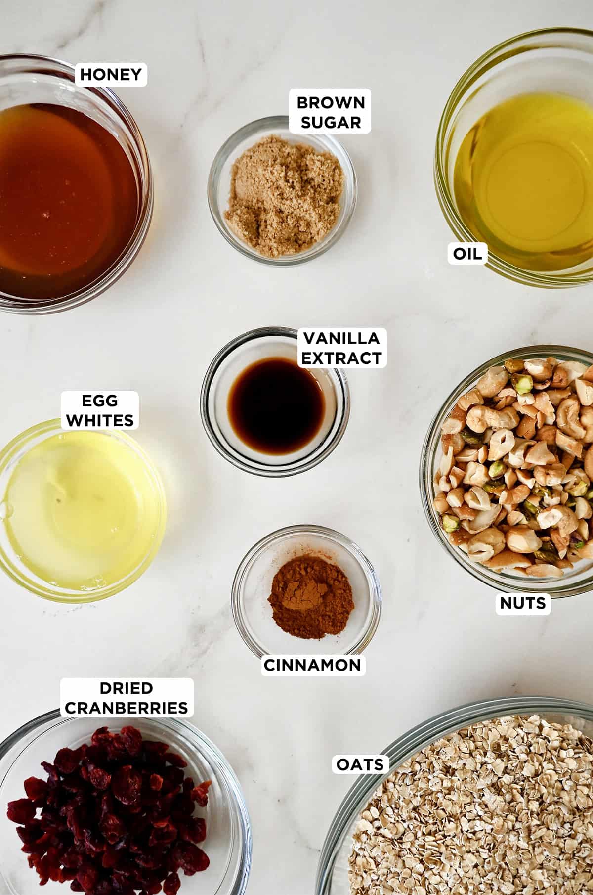 Ingredients to make granola in different sizes of glass bowls.