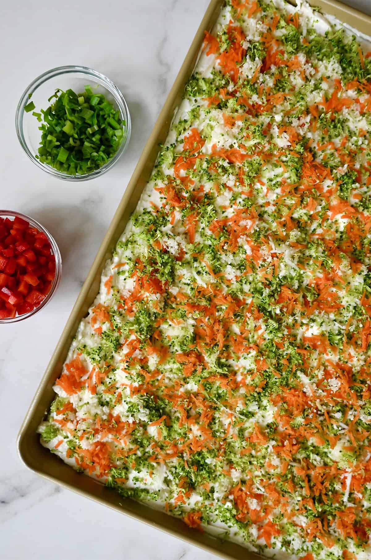 Topping cold veggie pizza with a rainbow of grated veggies.