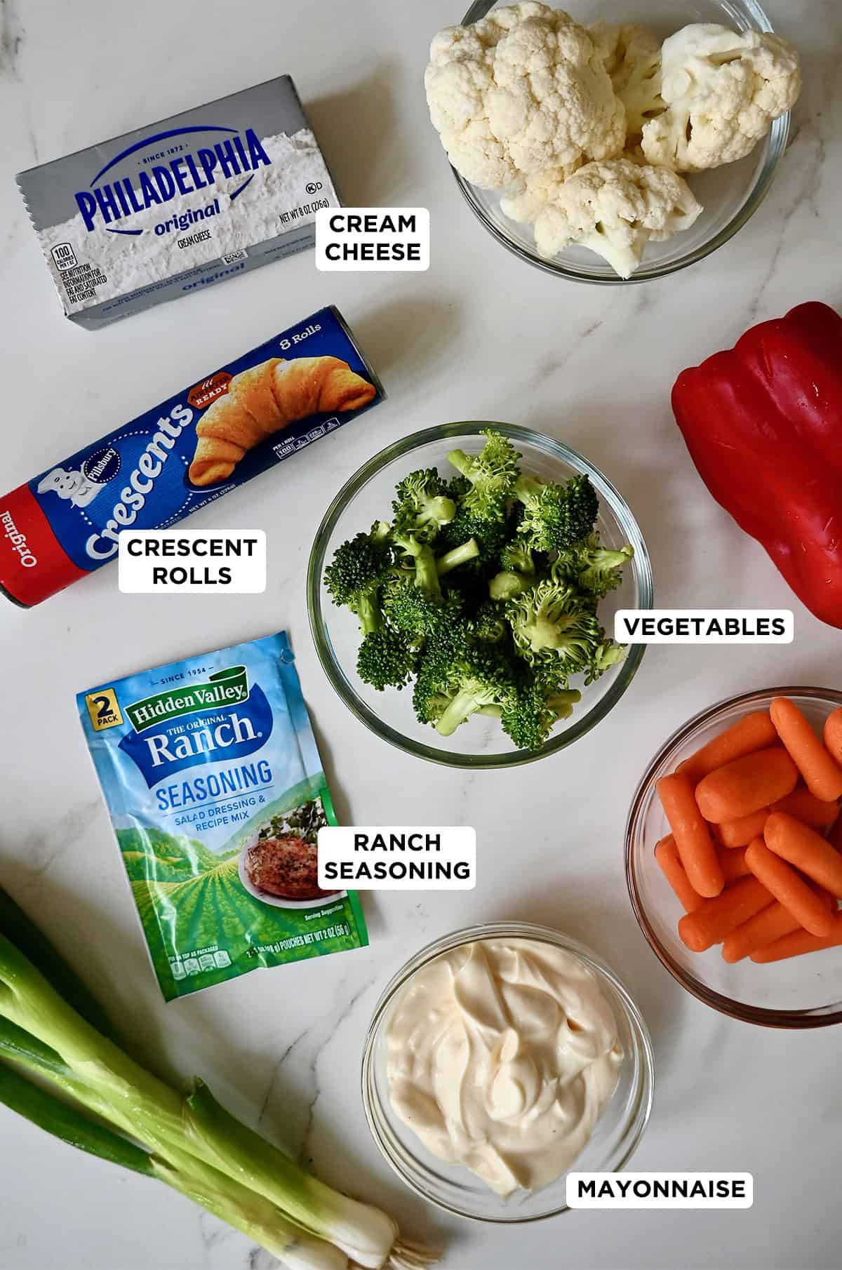 Cold veggie pizza ingredients, including a rainbow of vegetables, Hidden Valley Ranch Seasoning, cream cheese, mayo and Pillsbury Crescent Rolls.