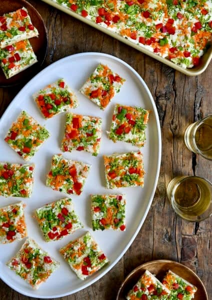 Crescent roll veggie pizza squares on a white serving platter.