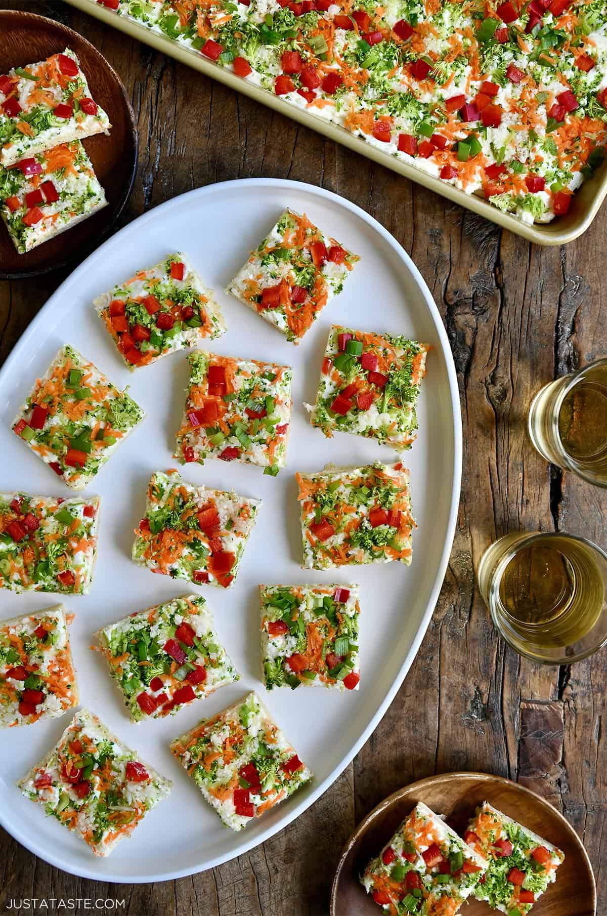 Crescent roll veggie pizza squares on a white serving platter.