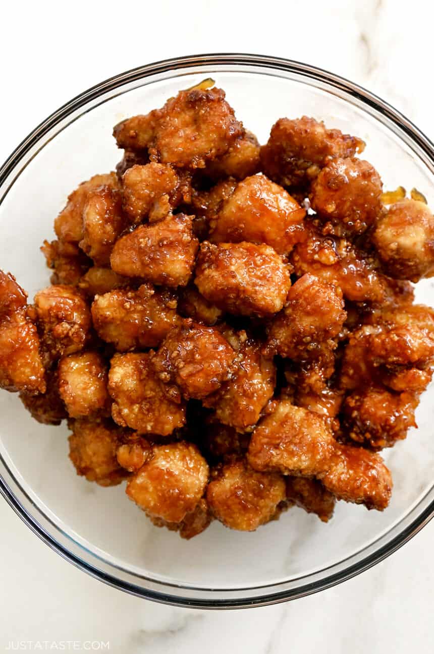 A top-down view of air fryer orange chicken in a clear bowl