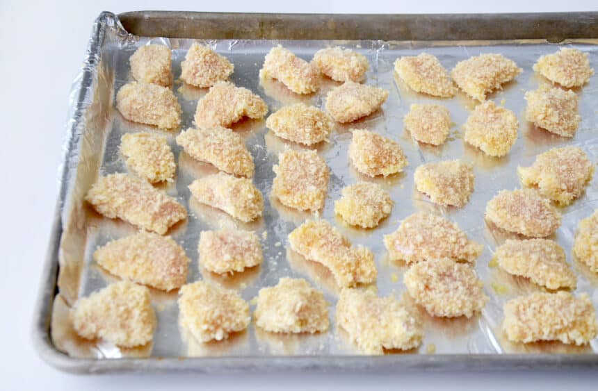 Chicken nuggets atop an aluminum foil-lined baking sheet