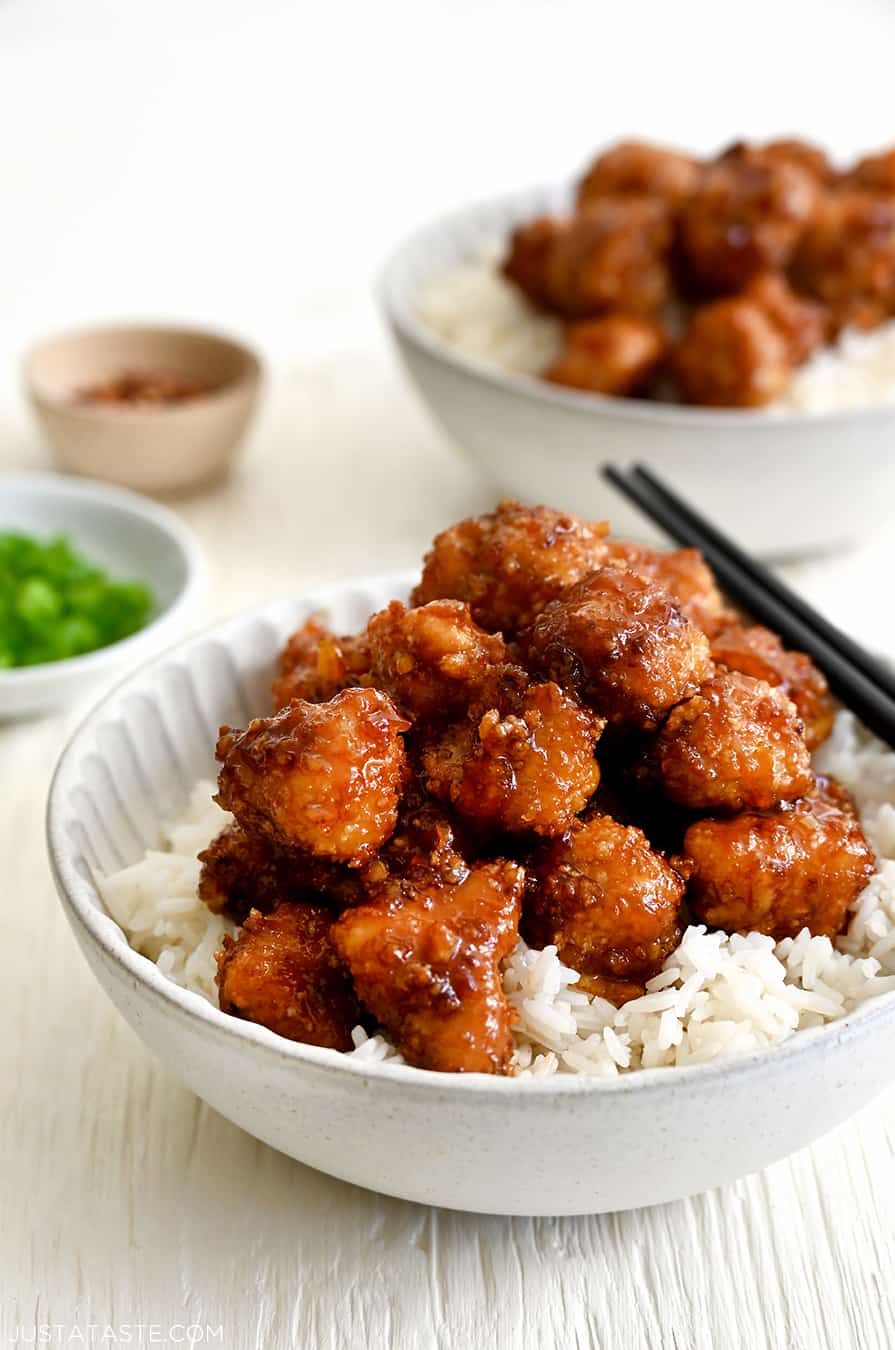 Baked Orange Chicken atop white rice in a bowl with chopsticks