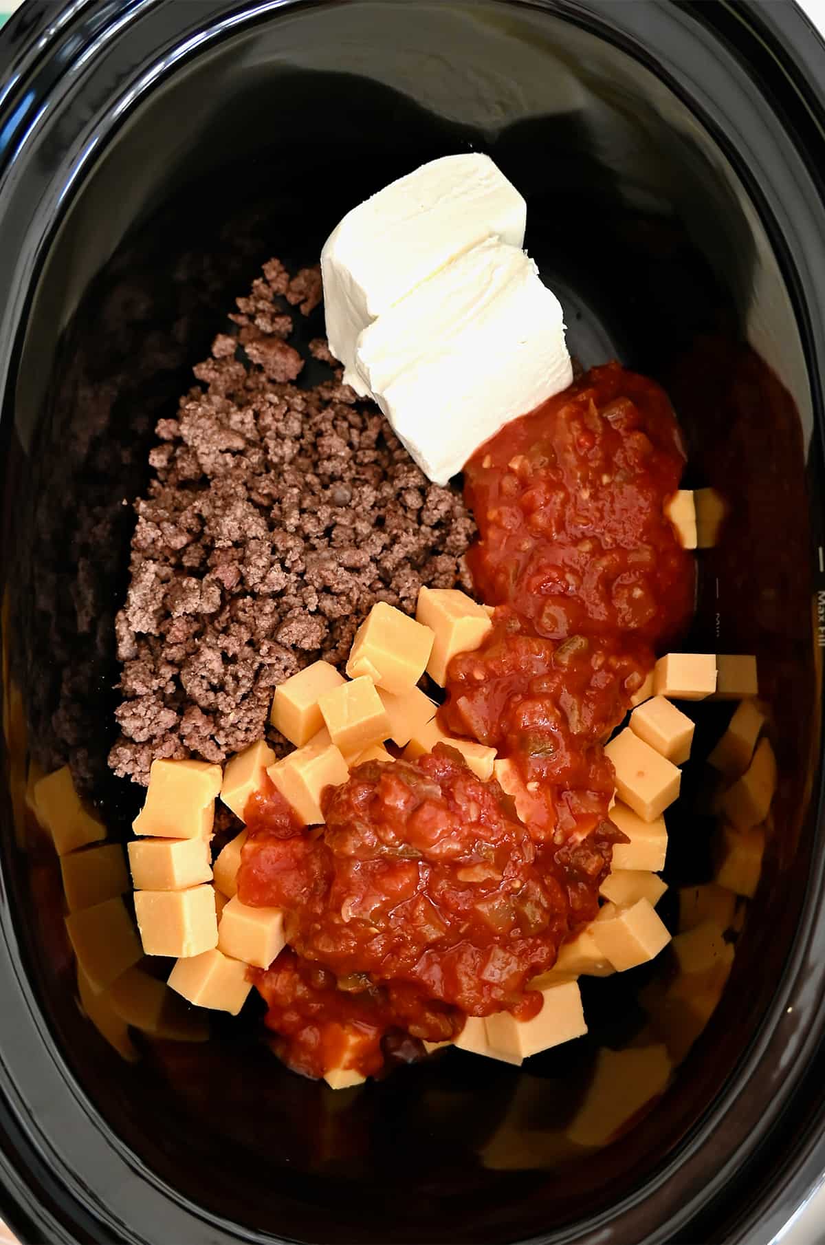 Browned ground beef, cream cheese, cubed cheddar cheese and chunky salsa in a slow cooker.
