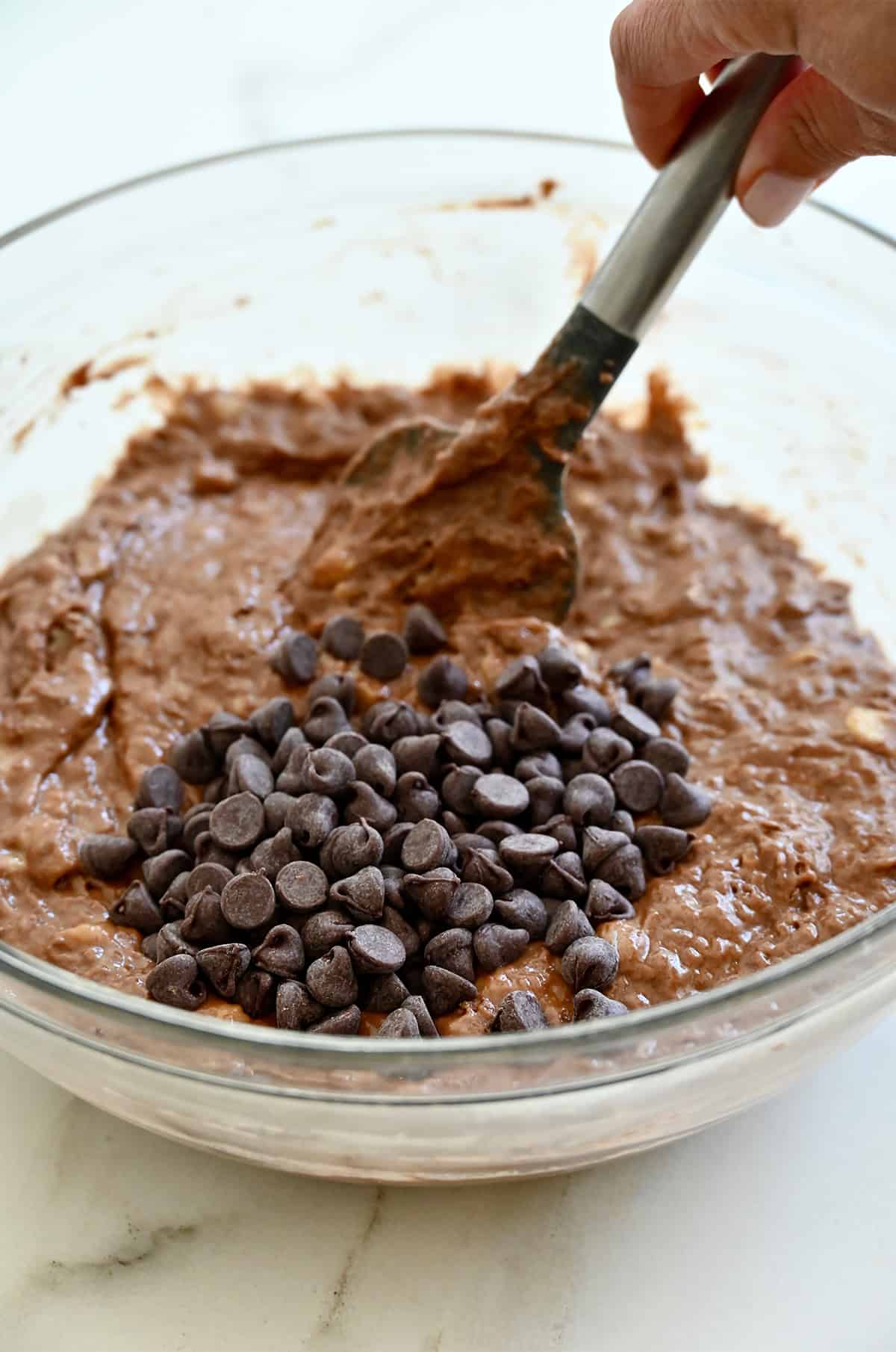 Folding chocolate chips into a chocolate banana bread batter.