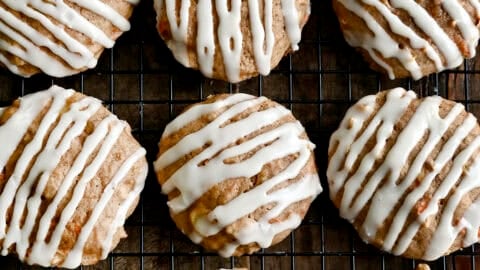 Thick carrot cake cookies drizzled with cream cheese icing on a wire cooling rack.