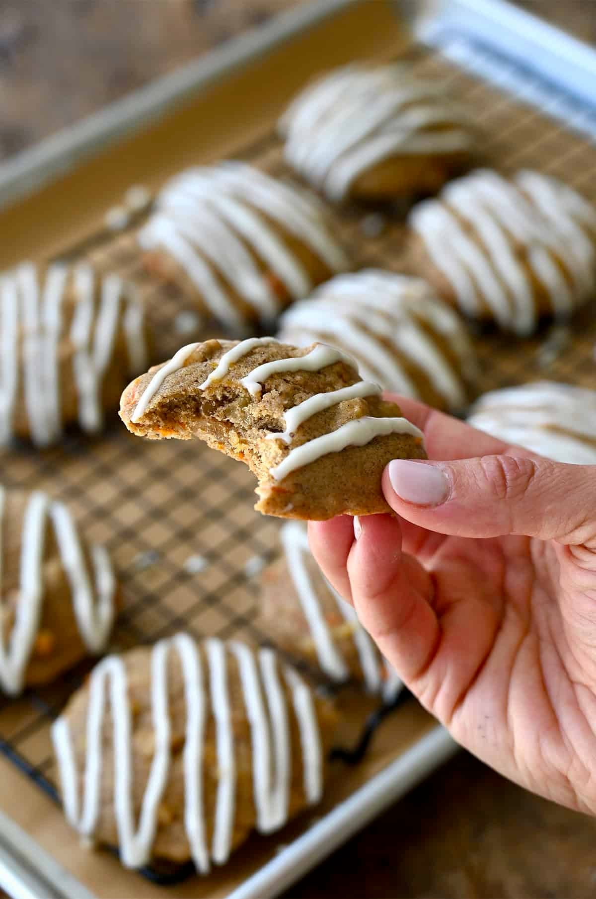 A carrot cake cookie with a bite taken out of it.