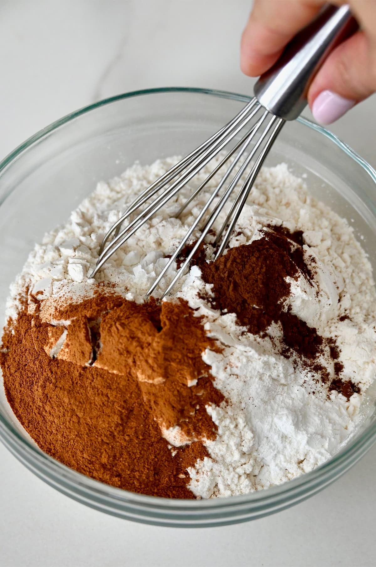 Dry ingredients for carrot cake cookies in a bowl with a whisk.