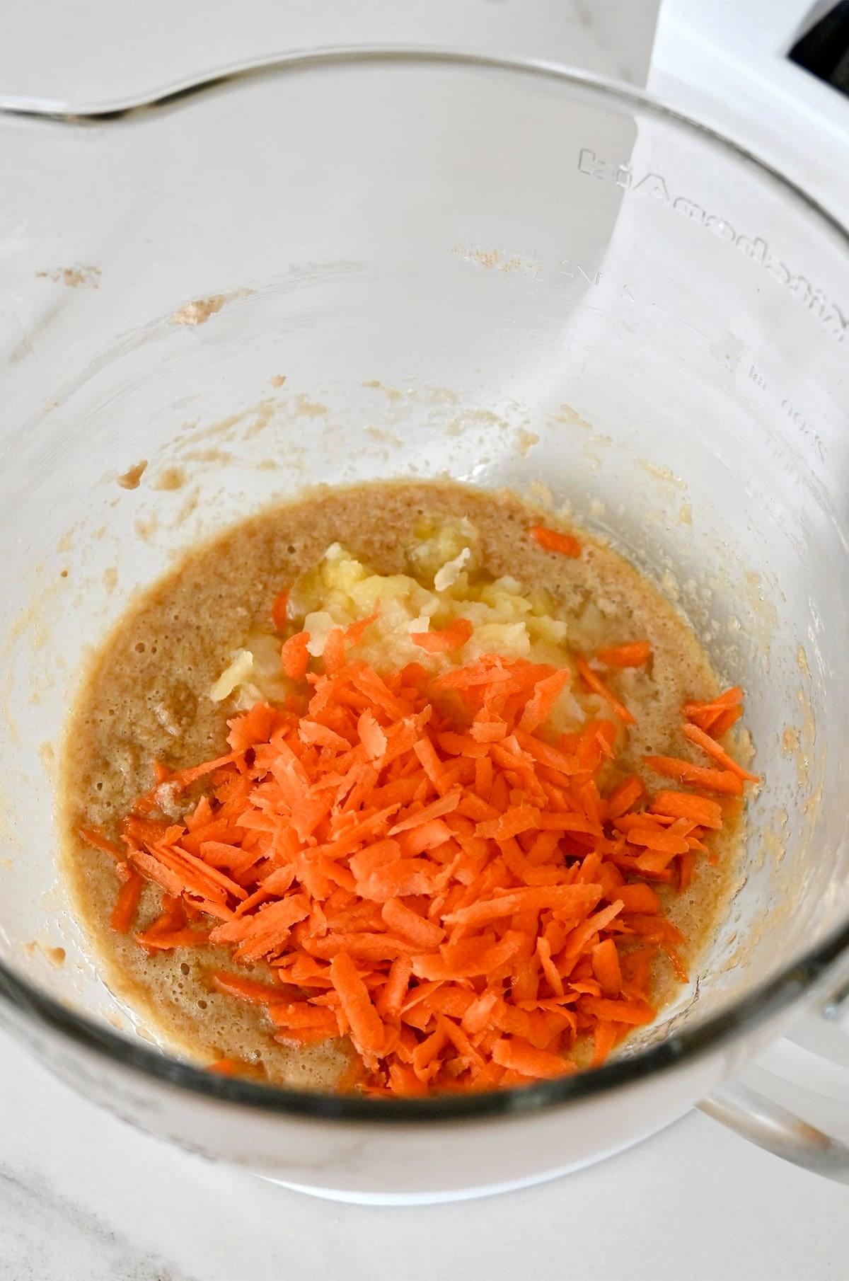 Shredded carrots and drained crushed pineapple in a bowl with the wet ingredients to make carrot cake cookies.