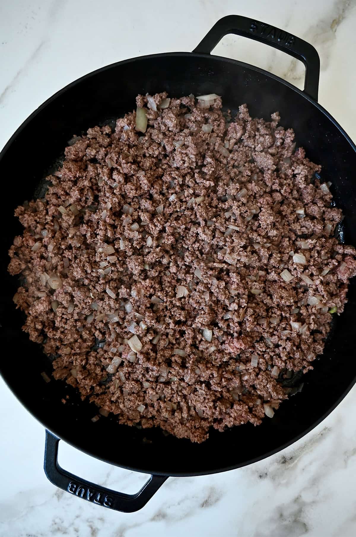 Browned ground beef in a cast iron skillet.