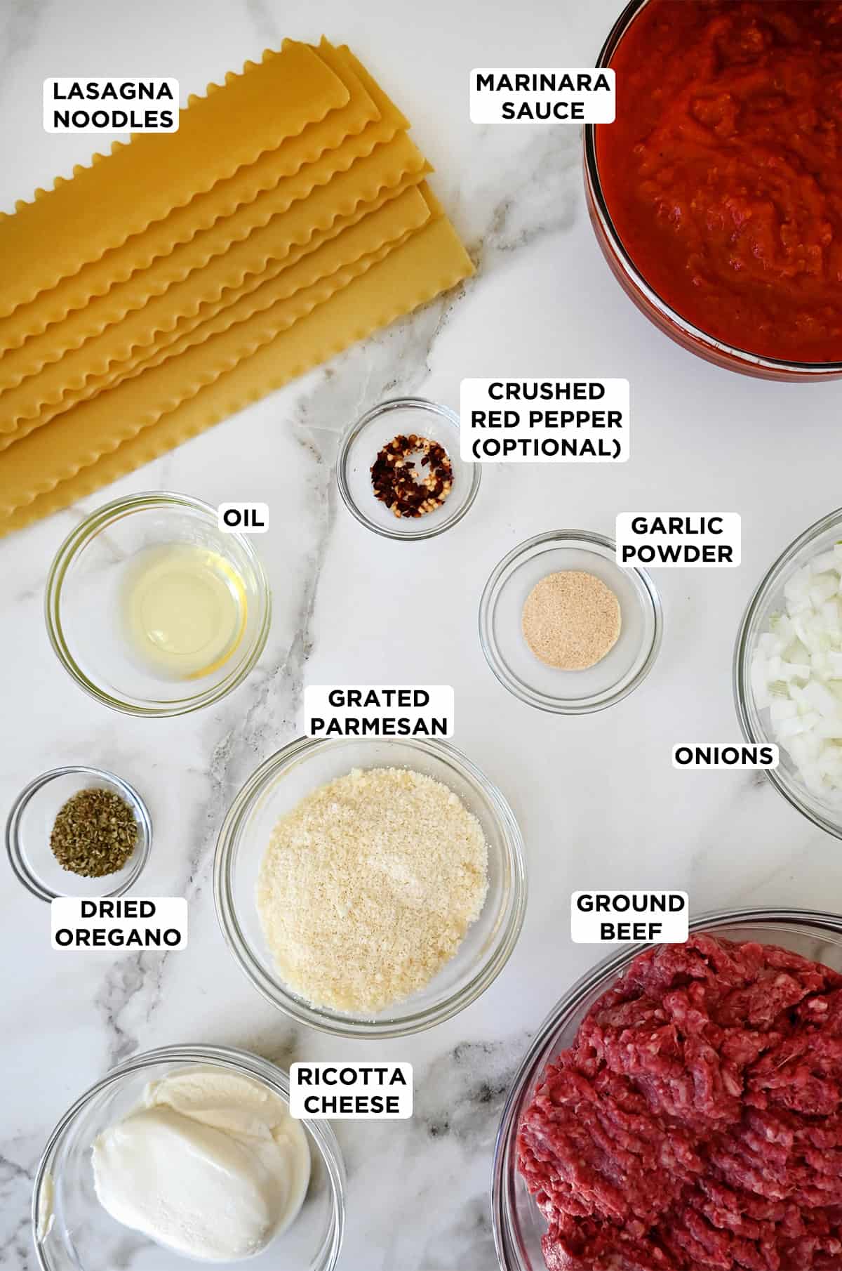 Ingredients for skillet lasagna: lasagna noodles, marinara sauce, crushed red pepper, garlic pepper, onions, ground beef, grated Parmesan, oil, dried oregano and ricotta cheese. 