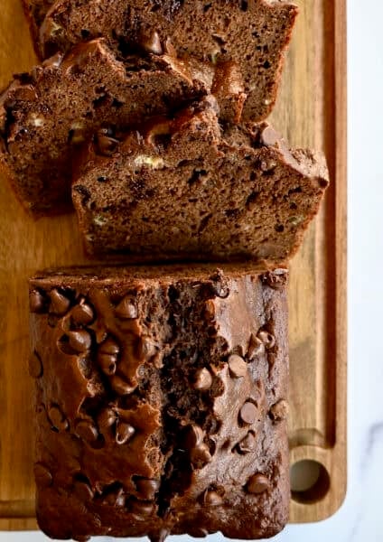A loaf of double chocolate banana bread with chocolate chips on a bamboo cutting board.