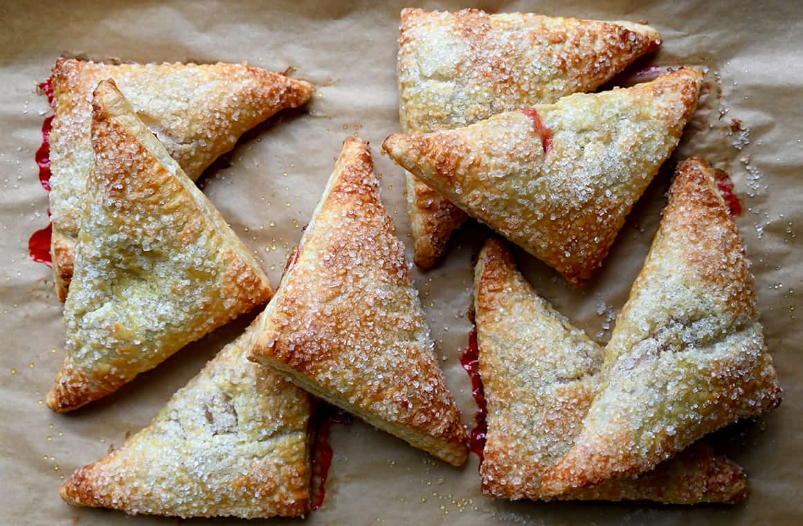 Freshly baked strawberry rhubarb turnovers with sanding sugar on parchment paper