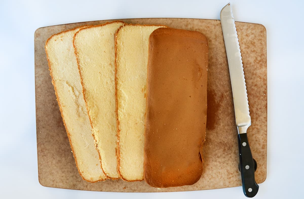 A top-down view of a sliced pound cake on a cutting board next to a serrated knife.