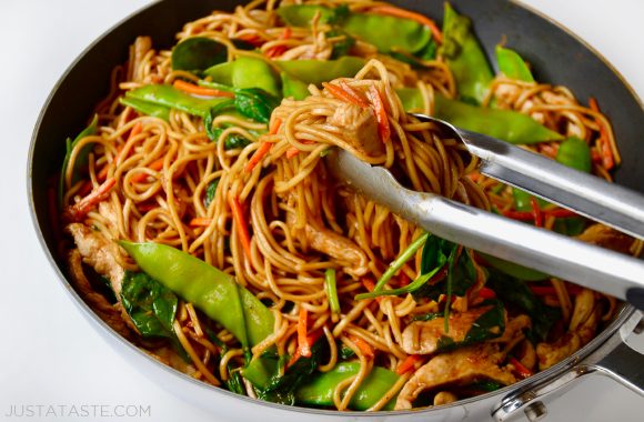 A skillet containing Chicken Lo Mein and tongs