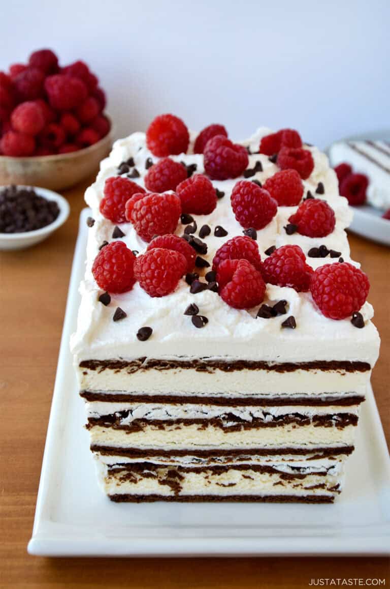 Ice cream sandwich cake with layers of whipped cream and topped with fresh raspberries and mini chocolate chips.