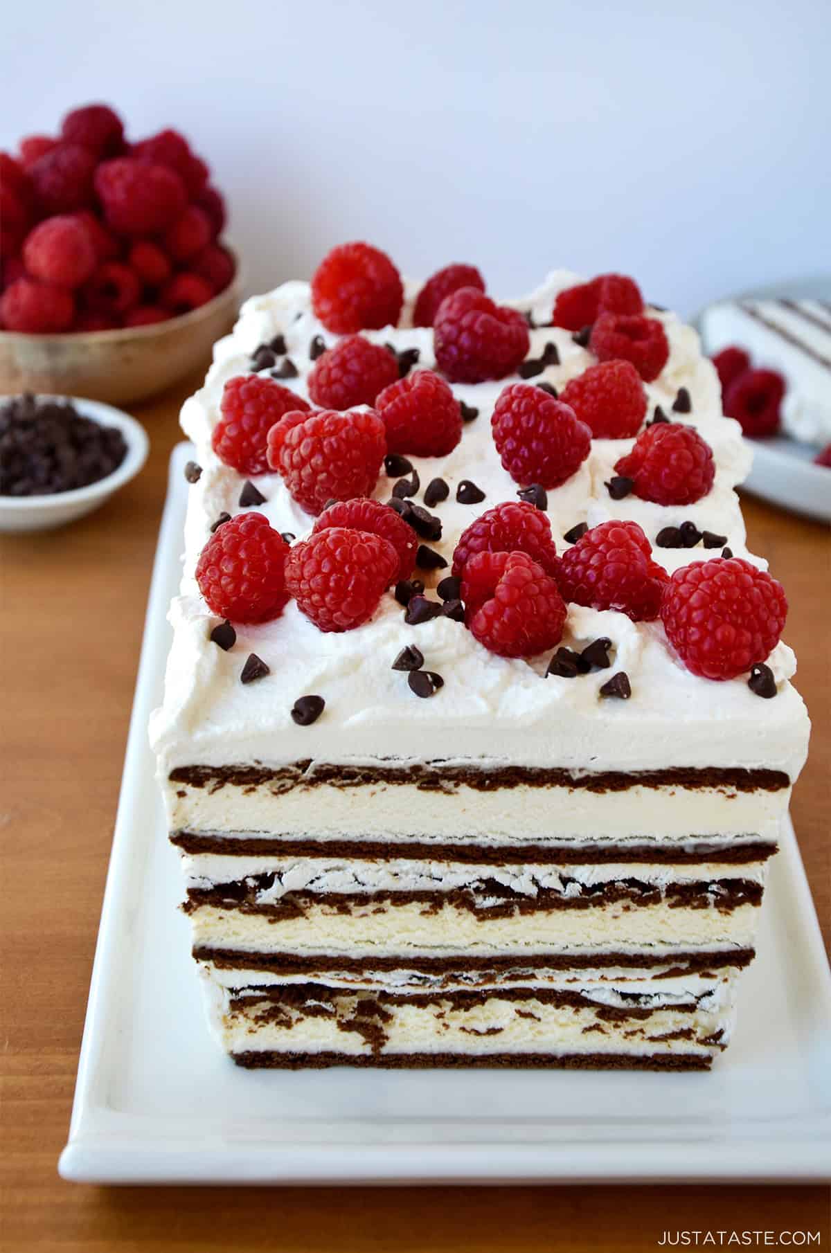 Ice cream sandwich cake with layers of whipped cream and topped with fresh raspberries and mini chocolate chips.