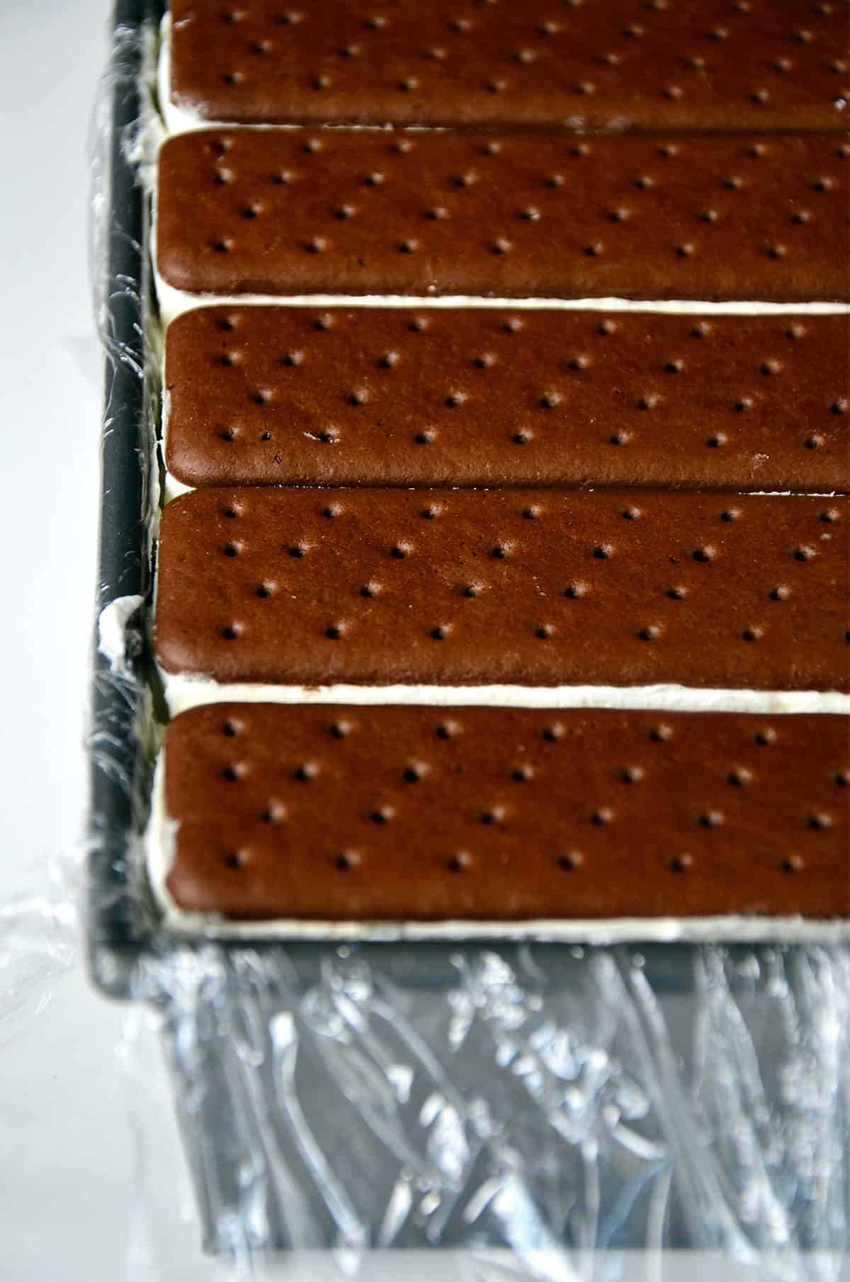 Ice cream sandwich cake in a loaf pan lined with plastic wrap.