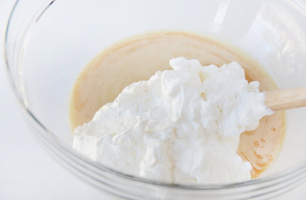 Folding whipped cream into sweetened condensed milk mixed with vanilla extract to make a no-churn ice cream base.