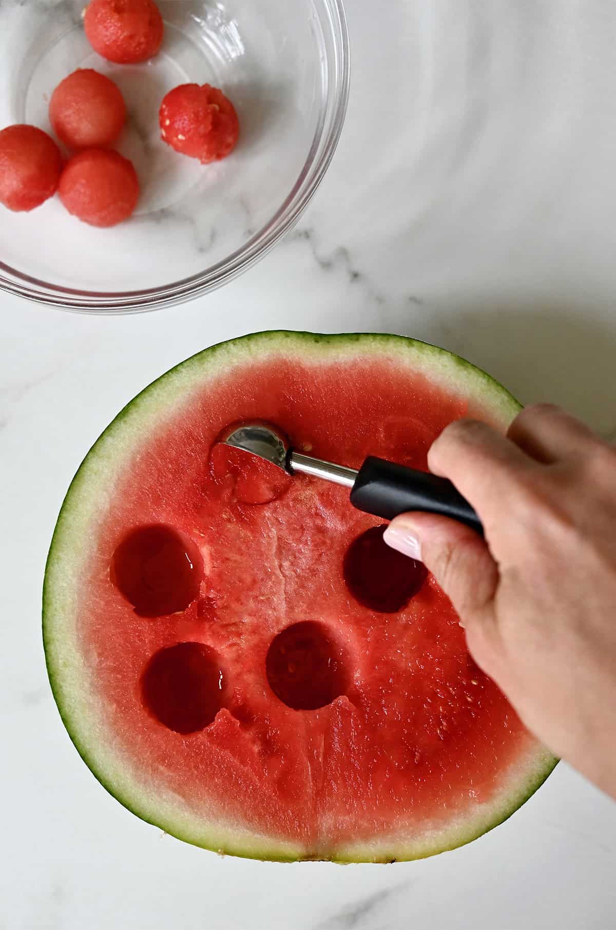 Using a melon baller to get perfect round balls of watermelon.
