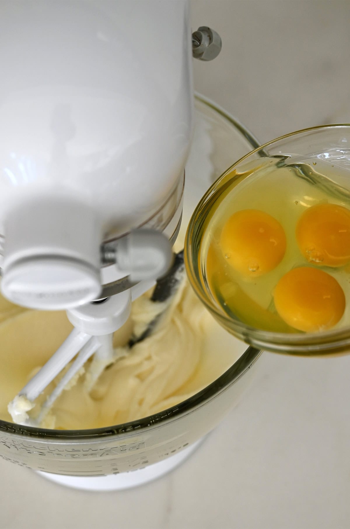 Adding eggs to creamed butter and sugar in a bowl.