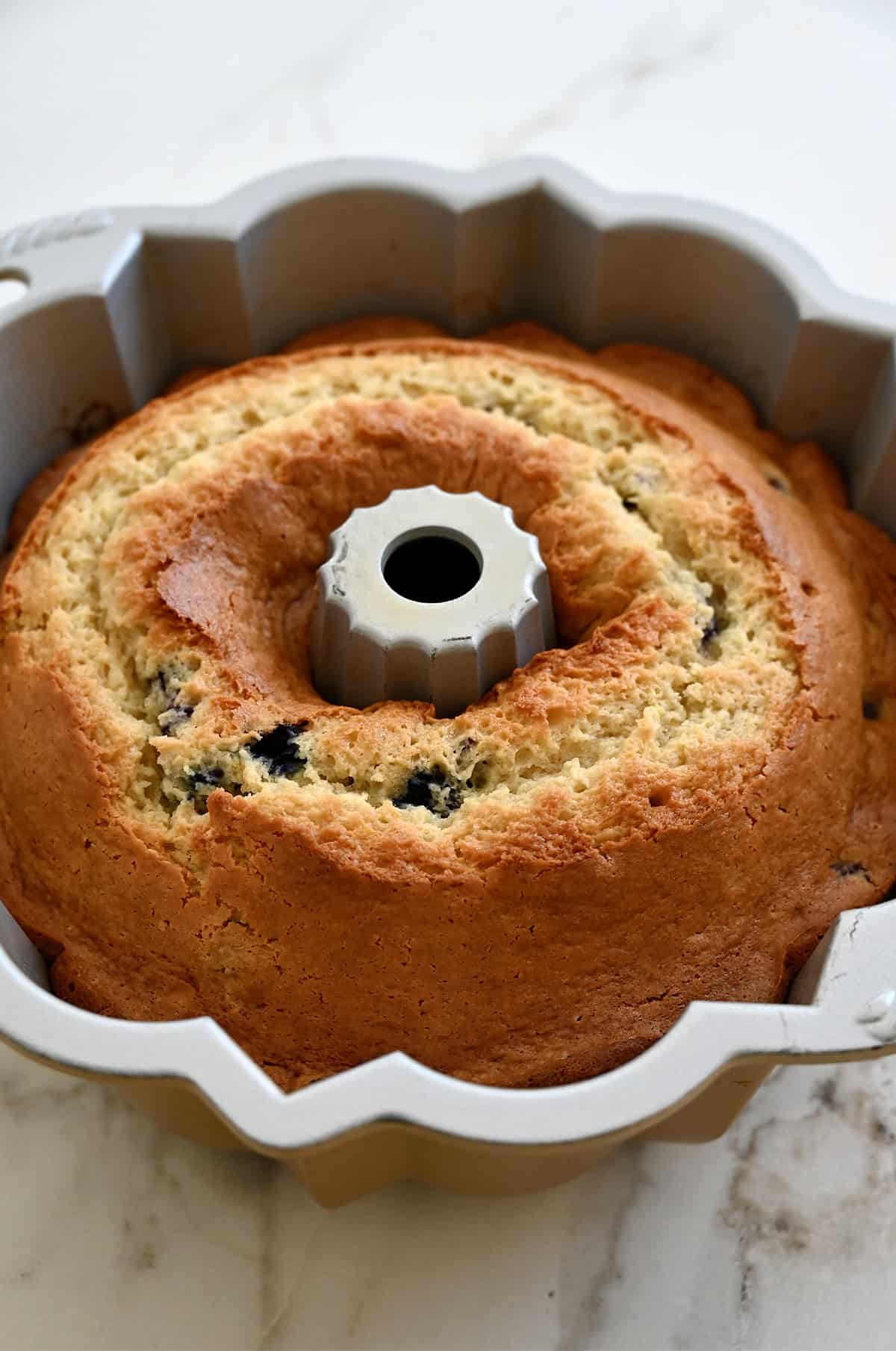 Freshly baked cream cheese pound cake with blueberries in a 10-cup bundt pan.