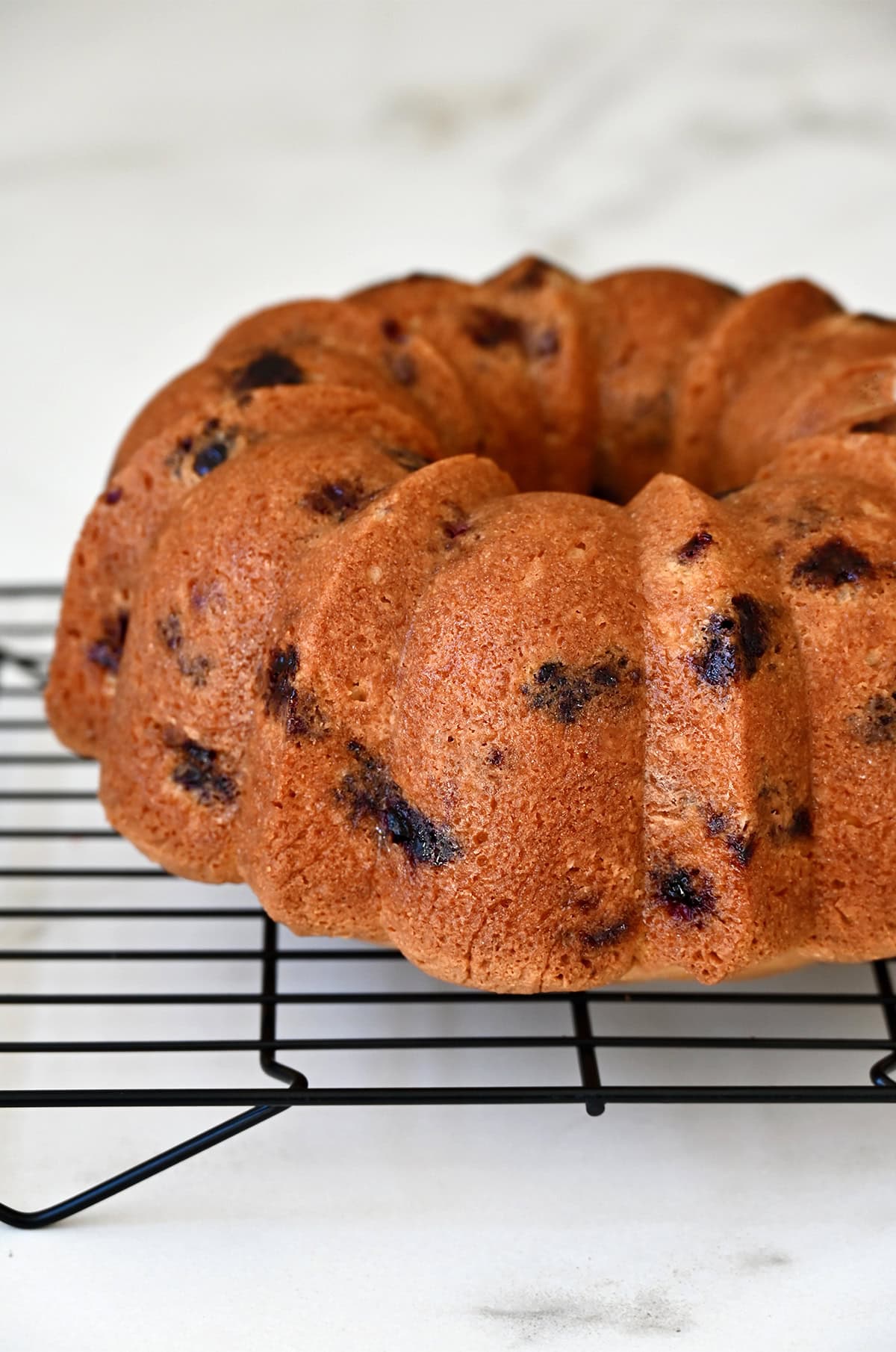 Lemon blueberry pound cake cooling on a wire rack.