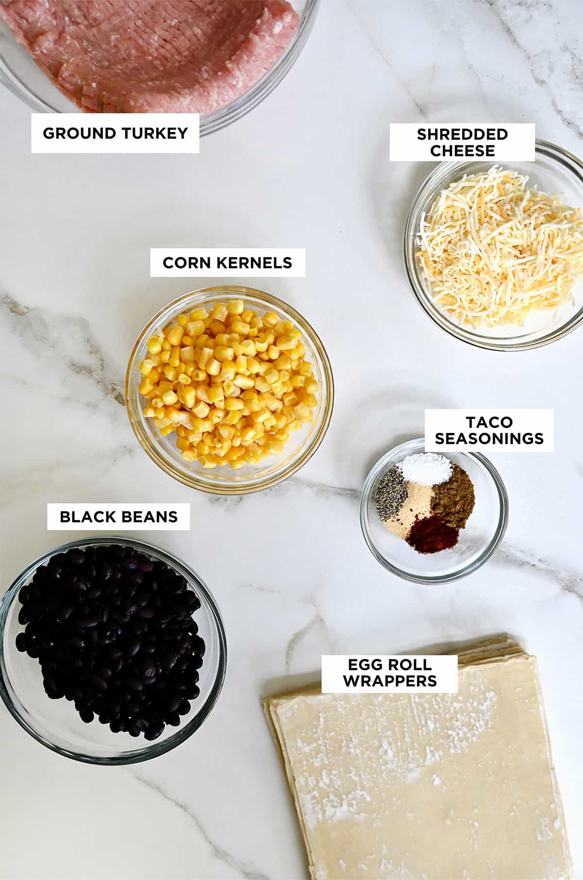 A top down view of glass bowls containing the ingredients for Southwestern egg rolls