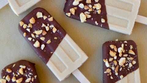 A top-down view of peanut butter frozen yogurt pops that have been dipped in chocolate and sprinkled with chopped peanuts.