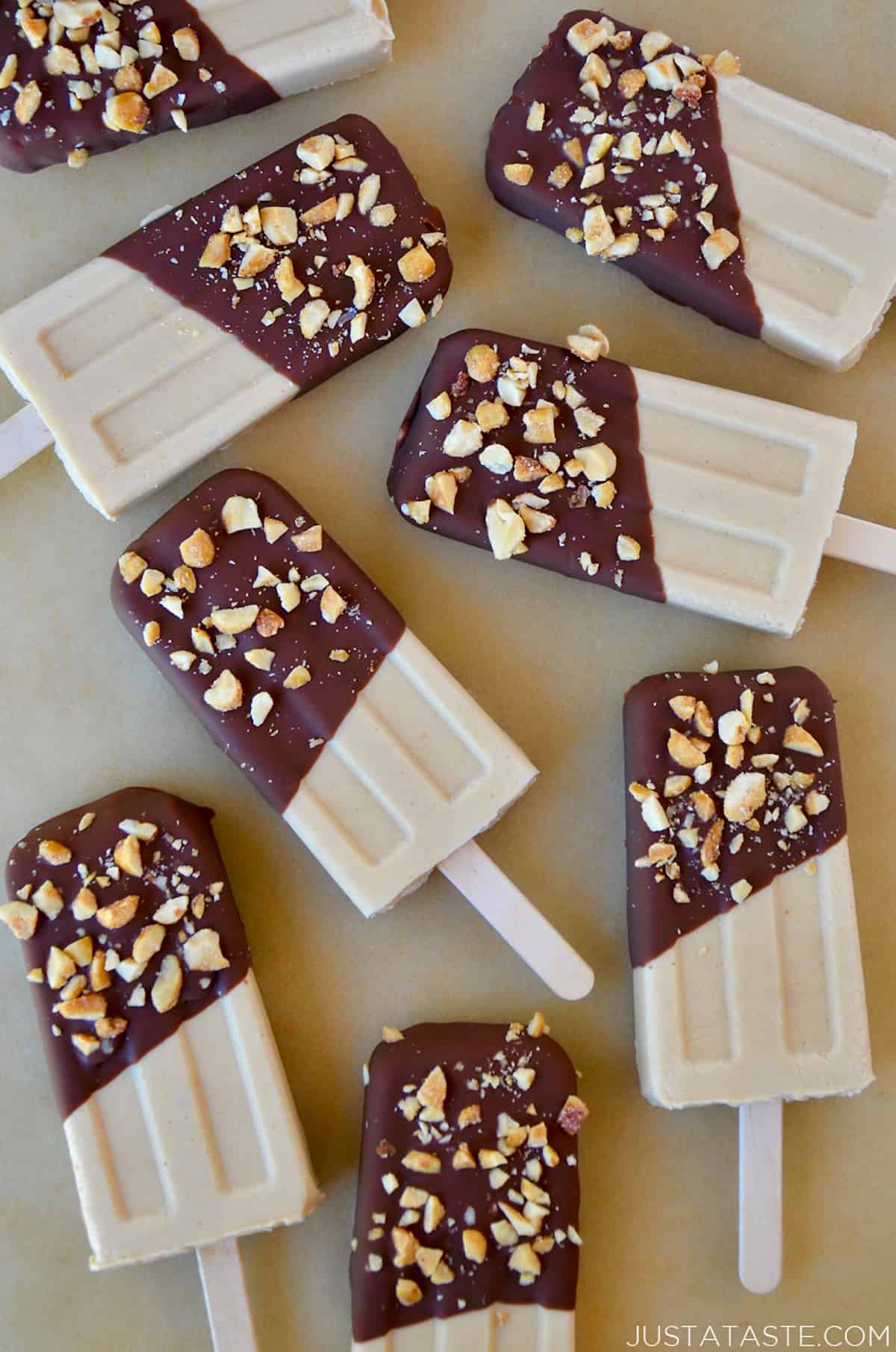 A top-down view of peanut butter frozen yogurt pops that have been dipped in chocolate and sprinkled with chopped peanuts.